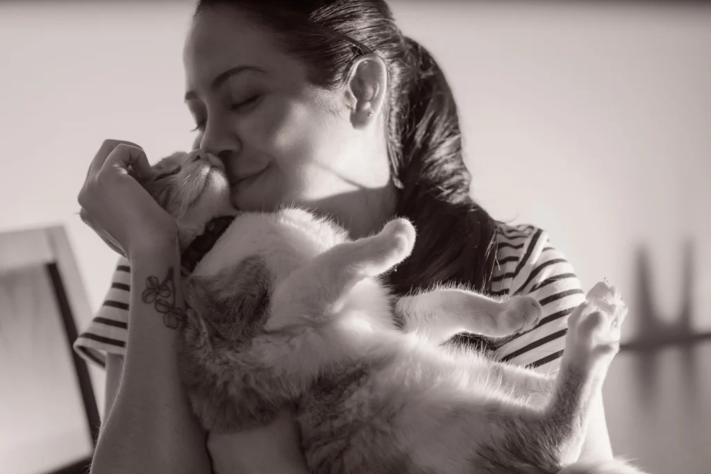12 Sinais de que Você é um Excelente Tutor e que o Gato Te Escolheu 3 Mulher abraçando e beijando seu gato de forma carinhosa, ilustrando a dedicação e o amor necessários para ser um tutor excelente.